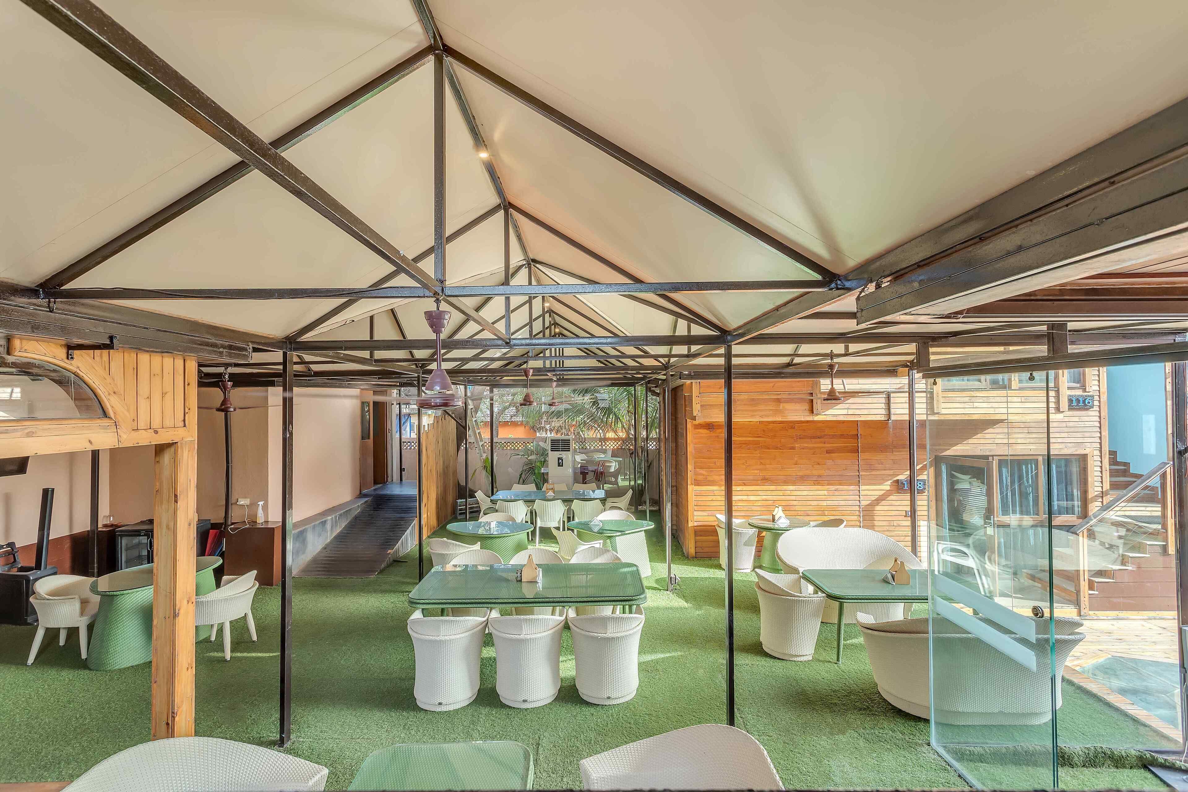 Un espacio interior amplio con mesas y sillas, una escalera y un muro de cristal.