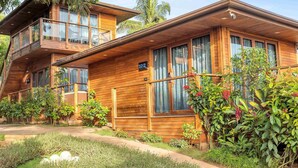 A wooden two-story house with a balcony, surrounded by lush greenery and a well-maintained garden. - The Baga Beach Resort (Baga)