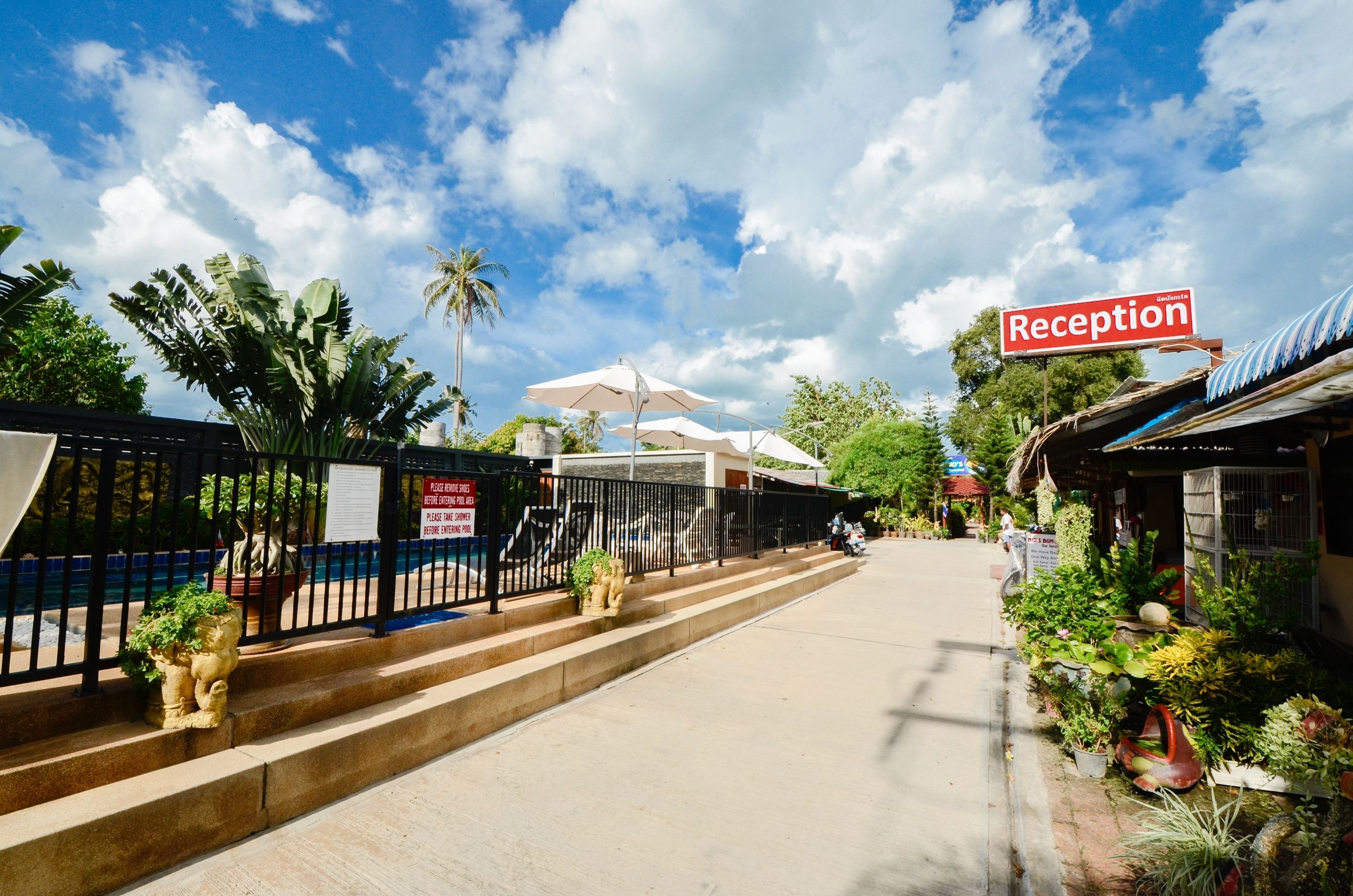 A reception area with a sign, steps leading up to a building, and potted plants.