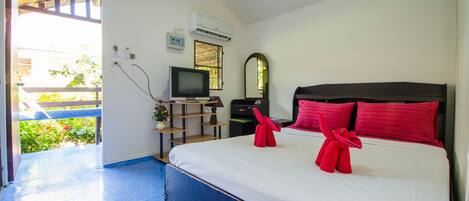 A hotel room with a bed, a television, a desk, and a window.