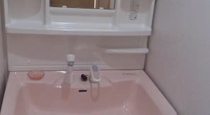 Un lavabo con grifo, dispensador de jabón y jabonera.