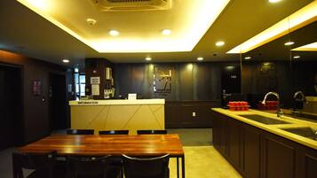 A modern kitchen with a wooden dining table and chairs, a built-in sink, and a counter with an information station.
