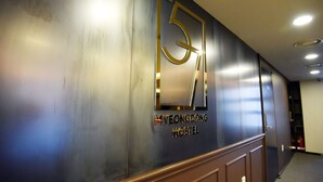 Un corridoio con un cartello appeso al muro che indica "Myeongdong Hostel" e un numero grande, "51".
