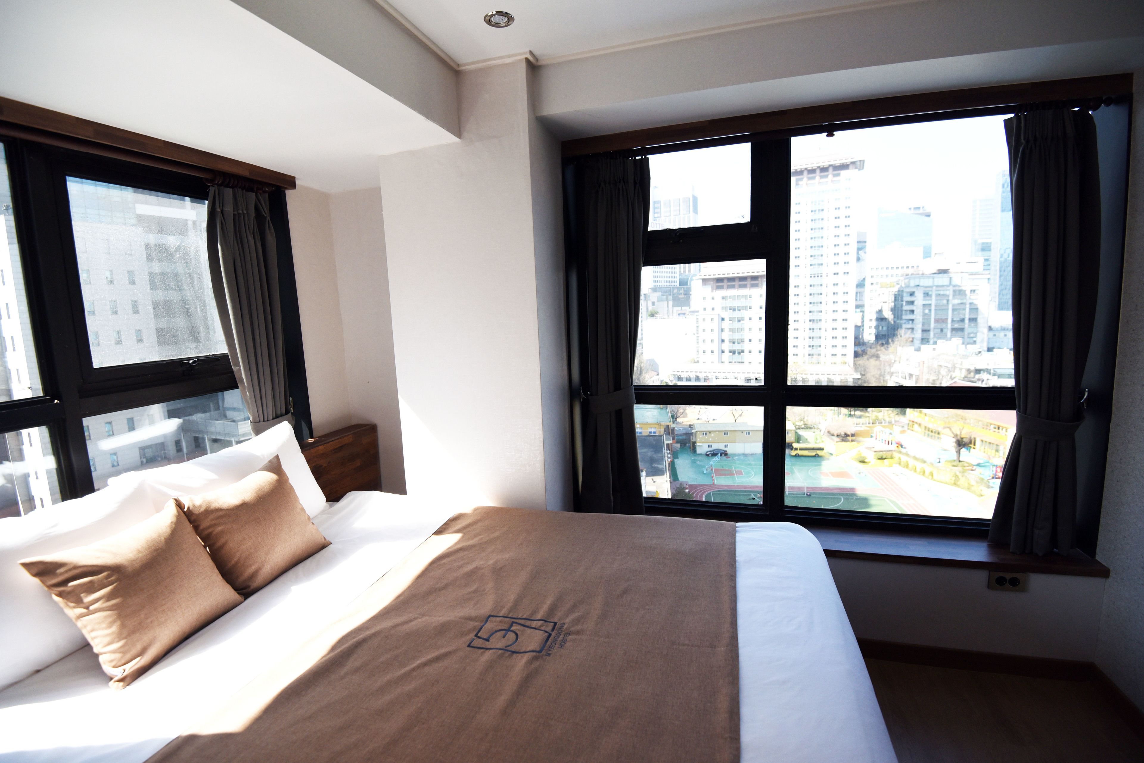 A hotel room with a large bed, a window with a city view, and a view of a sports field.