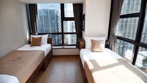 Camera d'albergo con due letti, ampie finestre e vista sulla città.