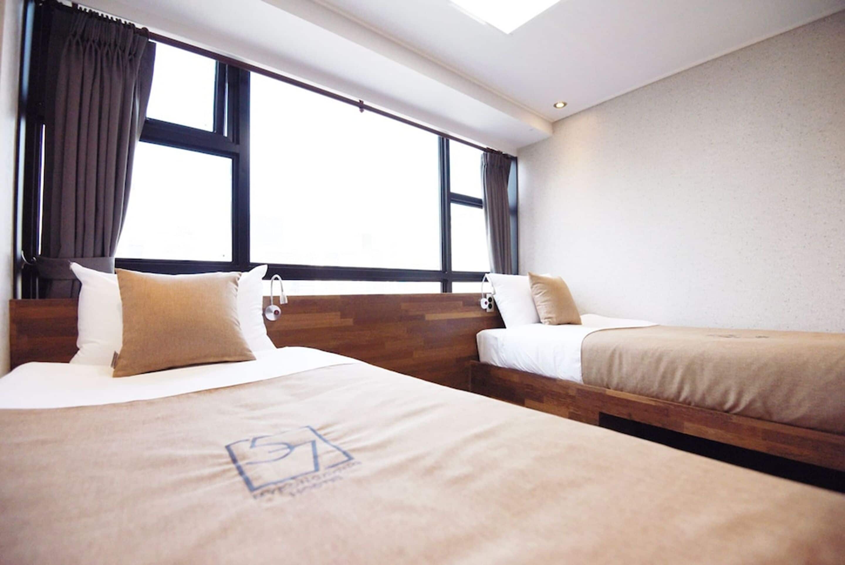 Une chambre d’hôtel avec deux lits, de grandes fenêtres et une lucarne.