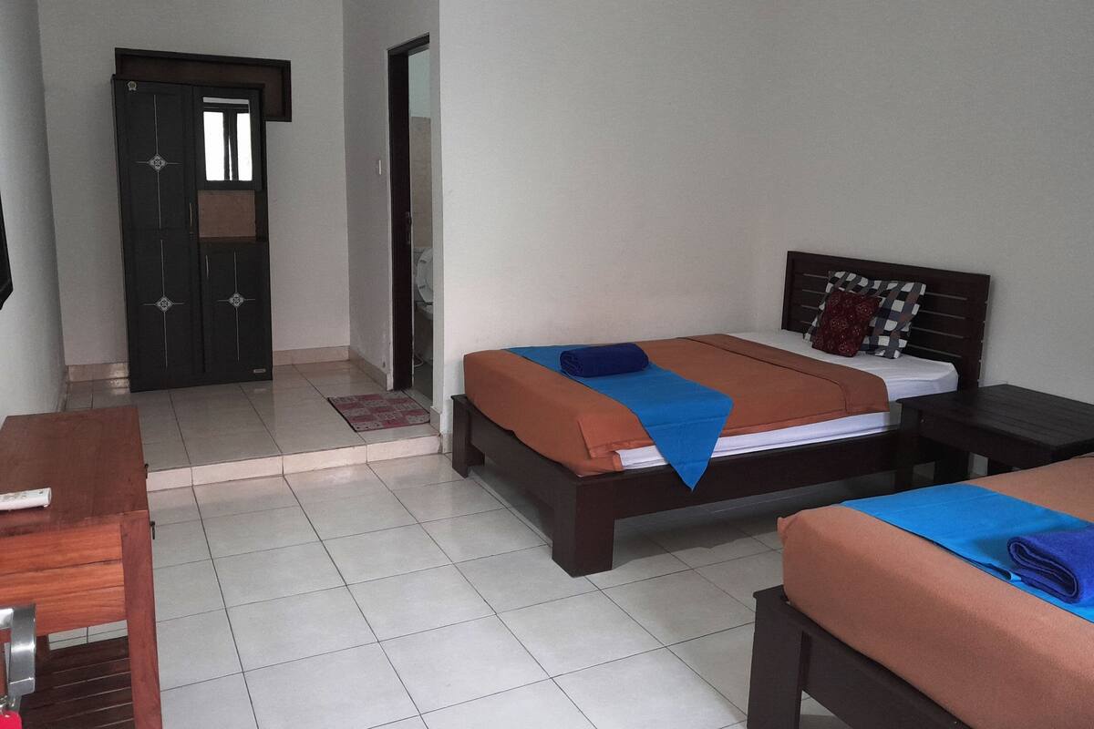 Une chambre d’hôtel comprenant un lit, des tables de chevet, un bureau en bois et une armoire.