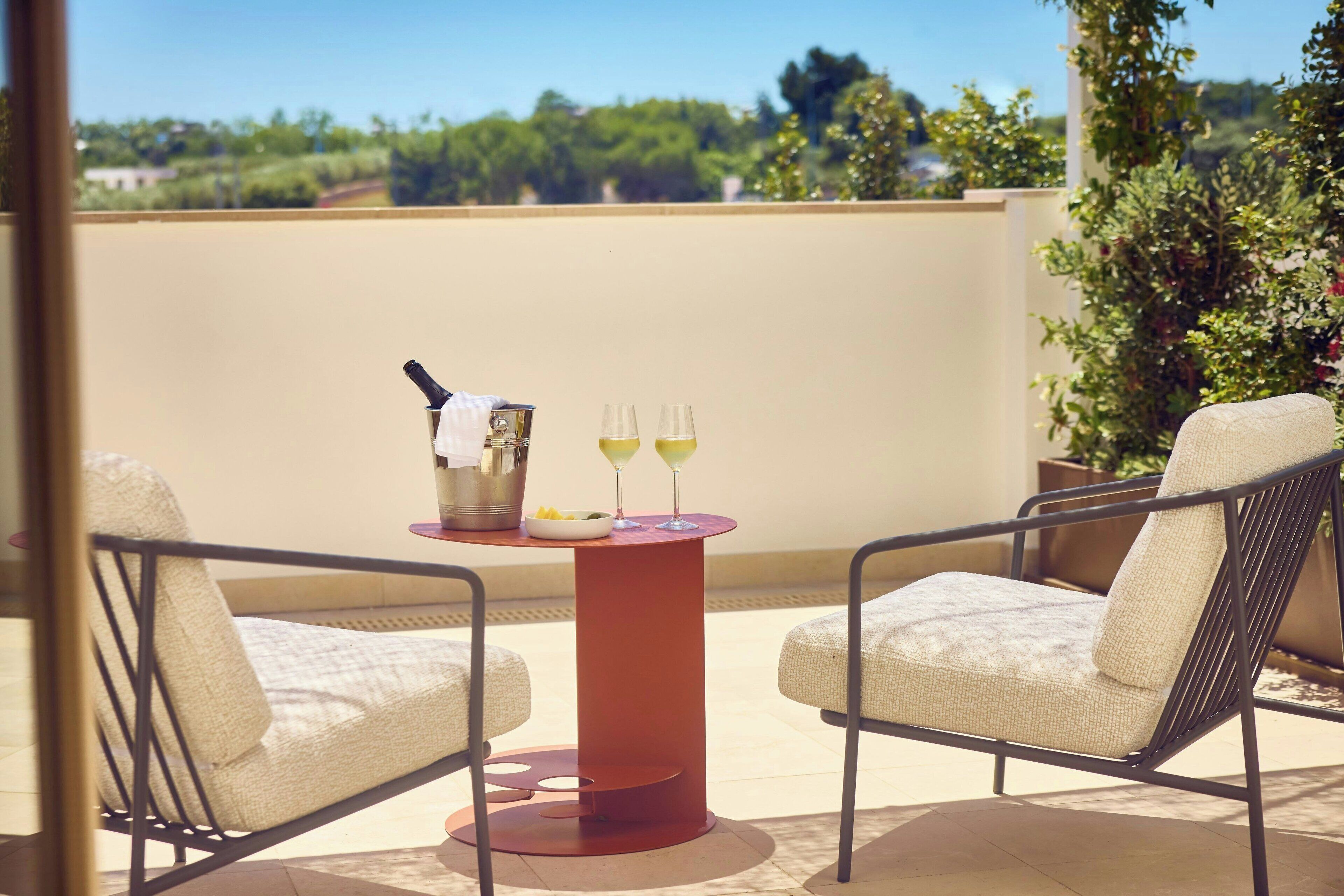 Ein Balkon mit zwei Stühlen, einem Tisch und zwei Gläsern mit Getränken.