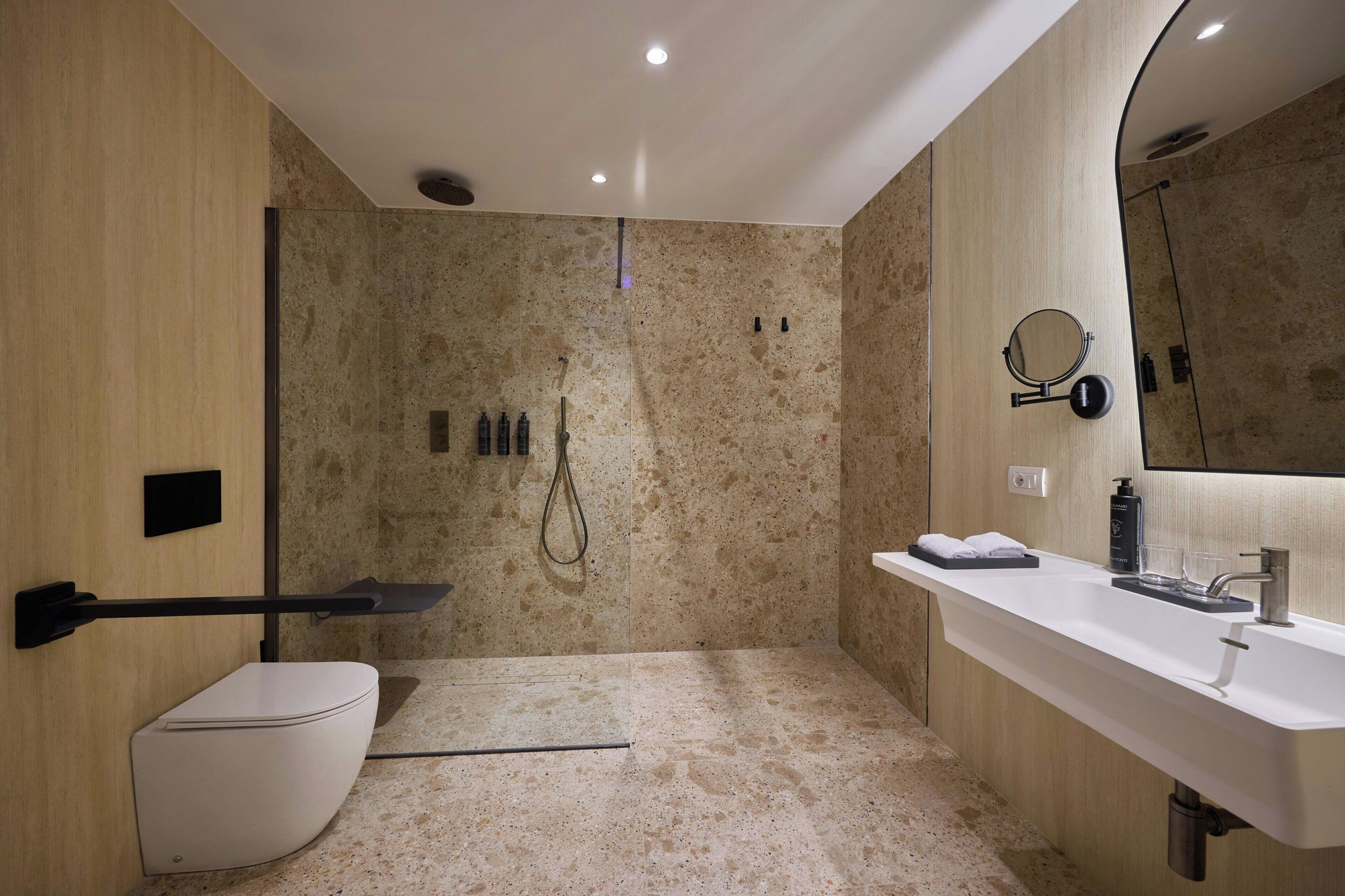 Een moderne badkamer met een douche, toilet en wastafel.
