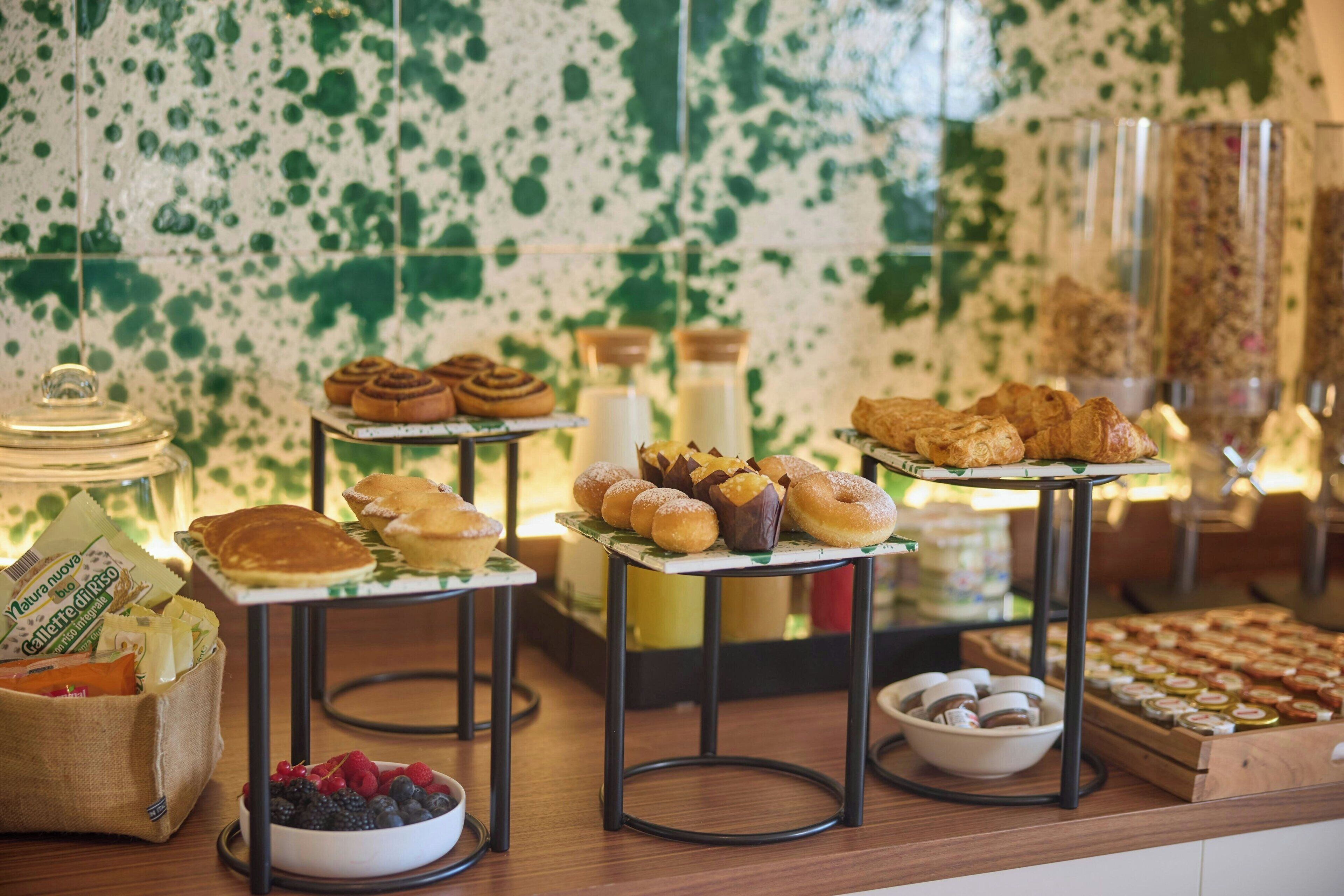 Ein reichhaltiges Buffet mit verschiedenen Backwaren und Desserts, darunter Croissants, Muffins und eine Schüssel Beeren.