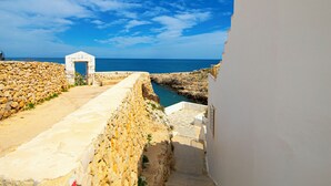 A stone staircase leading to a white building with a view of the sea. - Cala Ponte, a Tribute Portfolio Hotel (Polignano a Mare)