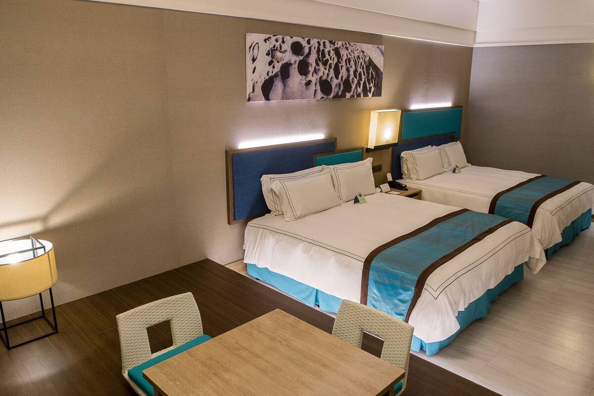 Une chambre d’hôtel avec deux lits, une table à manger et des chaises.