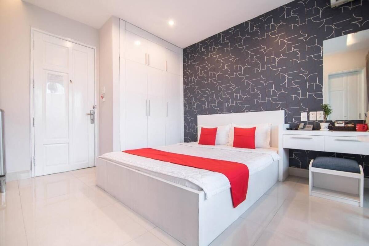 A modern bedroom with a large bed, a desk, and a wardrobe.