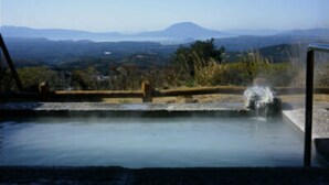 A hot spring with a wooden deck and a view of distant mountains. - Ryokojin Sanso (Kirishima)