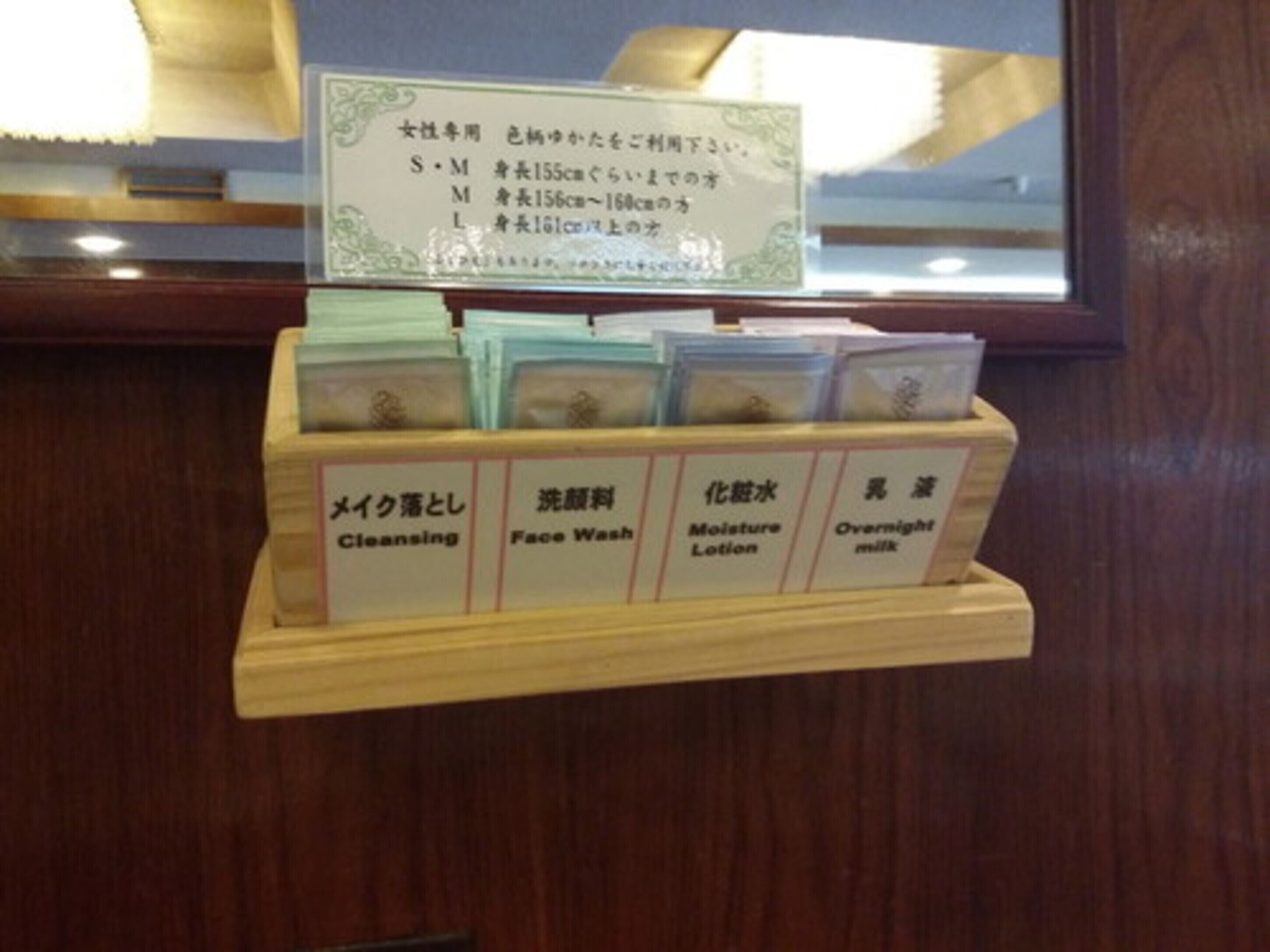 A wooden display with labeled compartments for skincare products including cleansing, face wash, moisture lotion, and overnight milk.
