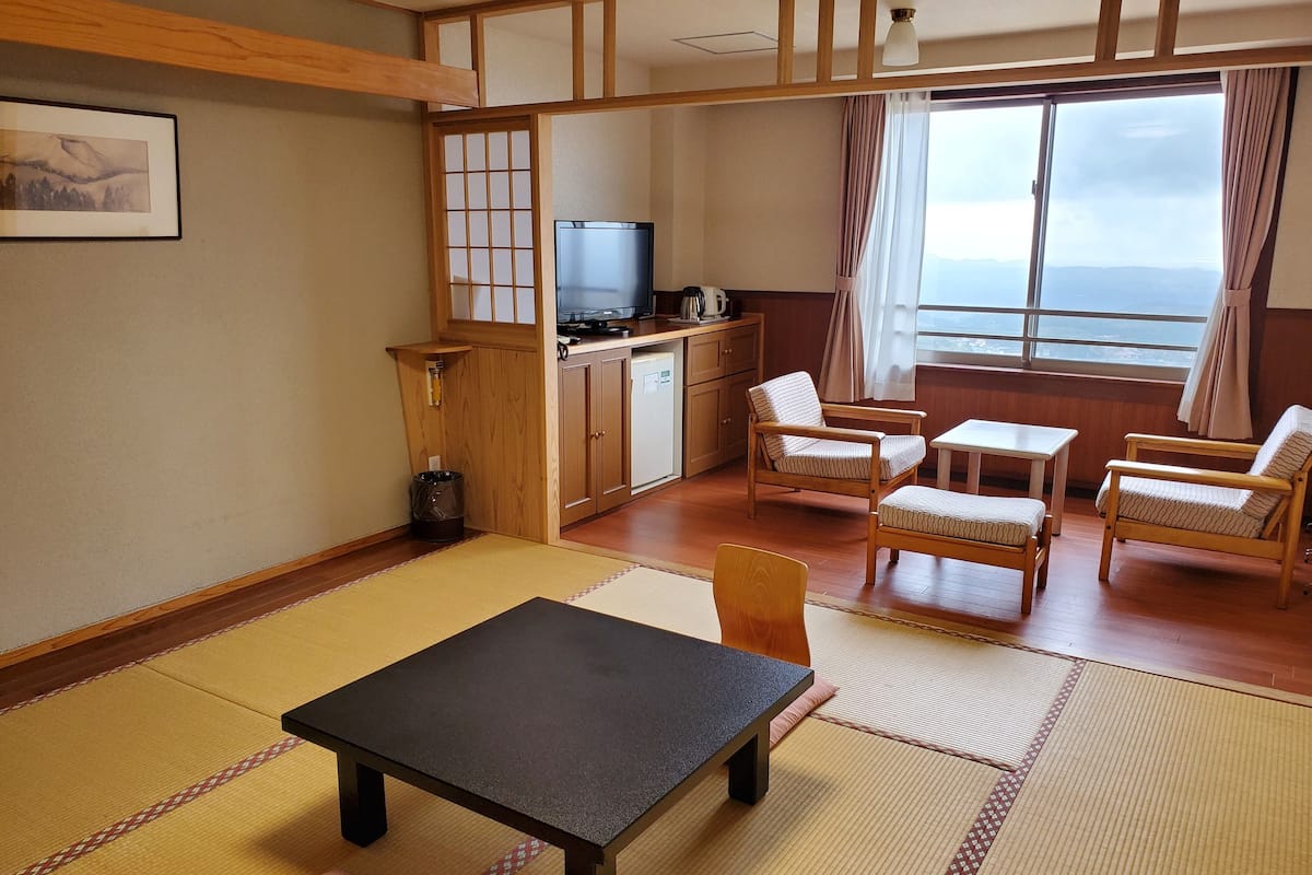 A traditional Japanese-style room with tatami flooring, a low table, and wooden furniture.