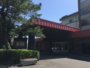 A building with a red overhang, a stone sign with Chinese characters, and a paved entrance area. - Ryokojin Sanso (Kirishima)