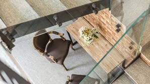 A modern dining area with a glass table, two chairs, and a floral centerpiece. - Corte San Martino (La Morra)