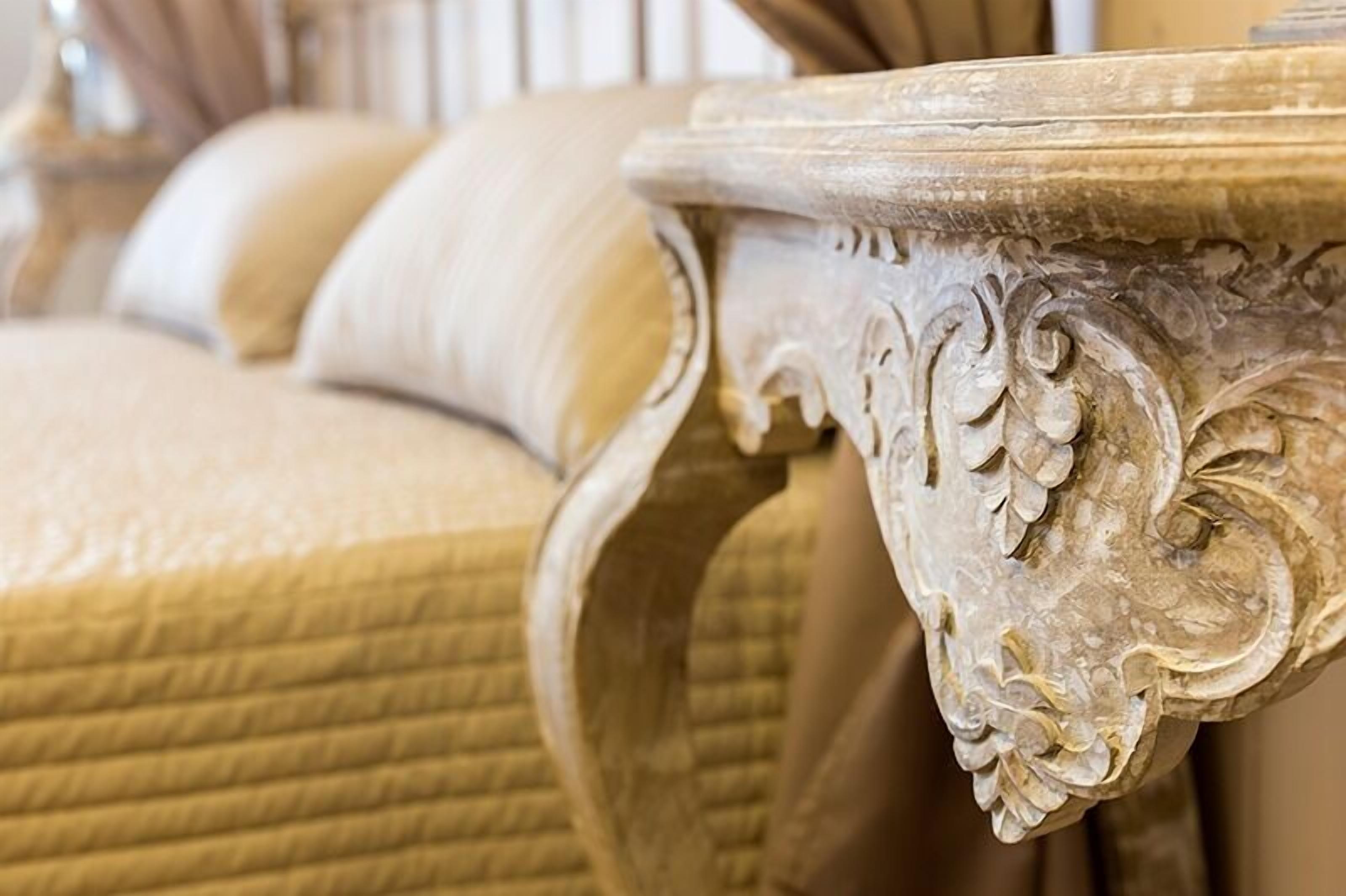 A close-up of a sofa with a textured fabric and a decorative metal frame with intricate carvings.