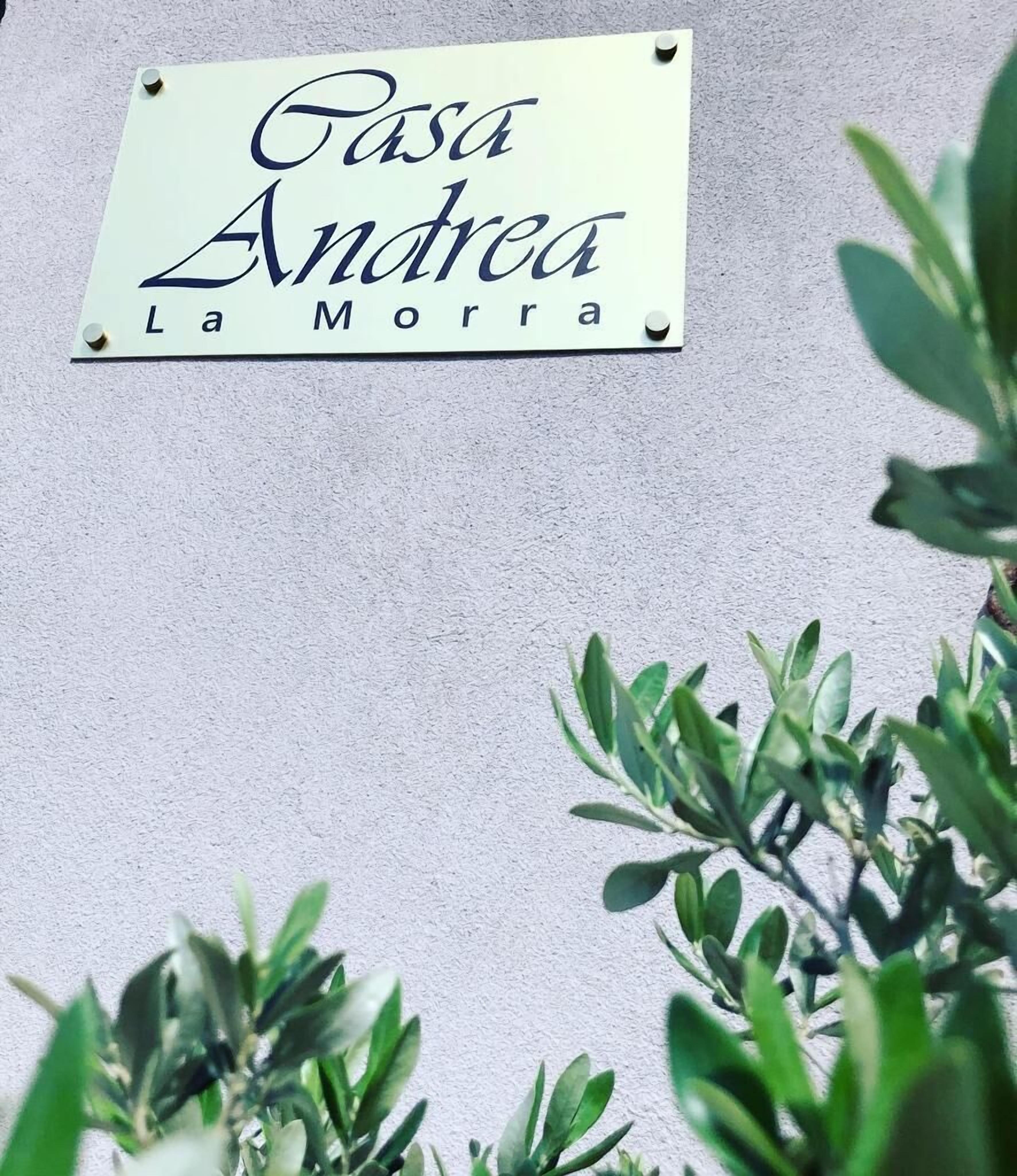 Une enseigne portant le nom « Casa Andrea La Morra » est fixée à un mur.