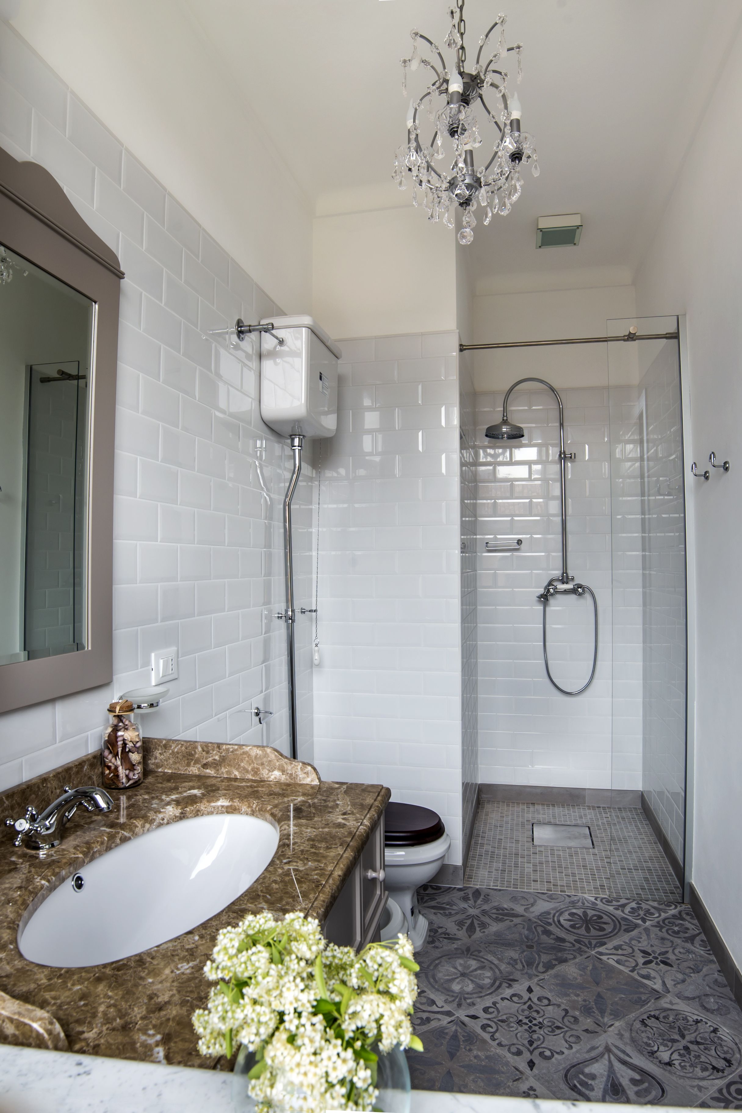 Un baño con lavamanos de mármol, inodoro, ducha y candelabro.