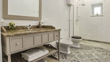 A bathroom with a vanity, sink, mirror, and shower.