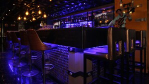 A bar area with stools and a counter, featuring hanging lights and a television screen. - Villa Caceres Hotel (Naga)