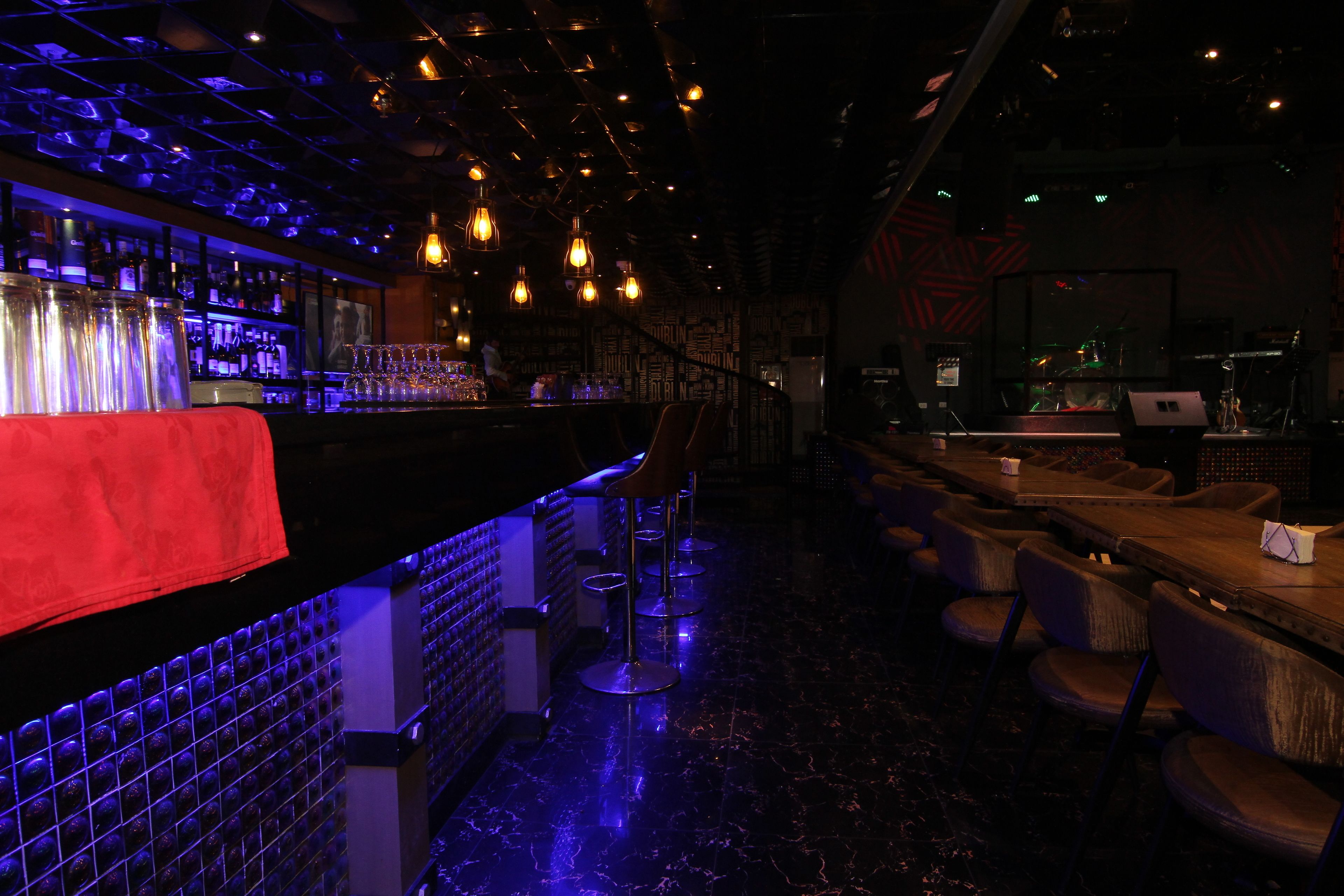 Een bar met een toonbank, barkrukken en een bakstenen muur.
