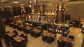 A restaurant with marble-topped tables and chairs, hanging pendant lights, and a bar area with various items on display. - Villa Caceres Hotel (Naga)
