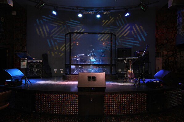 A stage with a drum set and a keyboard, surrounded by speakers and lighting equipment. - Villa Caceres Hotel (Naga)