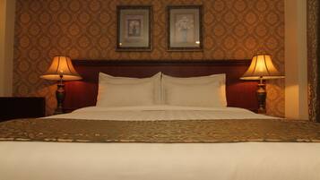 A hotel room with a large bed, two bedside lamps, a headboard, and two framed pictures on the wall.