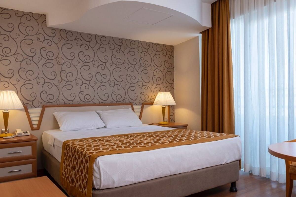 Ein Hotelzimmer mit einem großen Bett, zwei Nachttischlampen, einem Holznachttisch, einem kleinen Tisch und einem Stuhl.