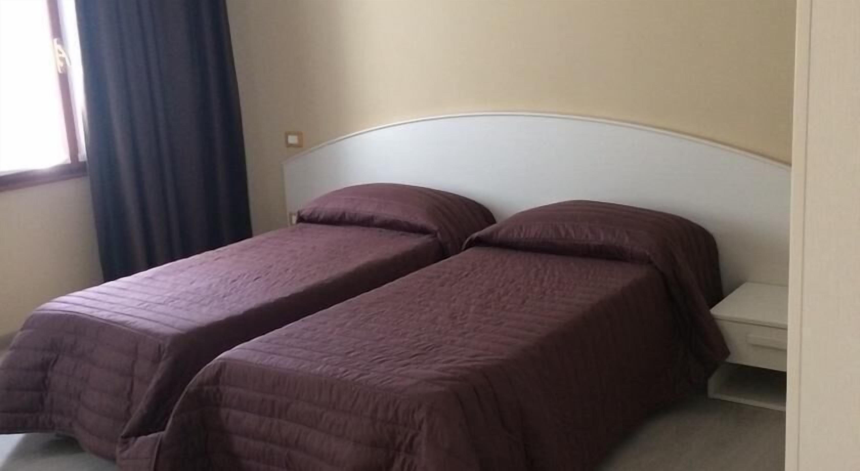 A room with two single beds, each with a headboard and a matching headboard.