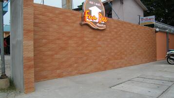 A sign for 'Fun Dee Mansion' with a brick wall and a motorcycle parked nearby.