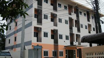 Un edificio de varios pisos con balcones y una entrada protegida por una reja.