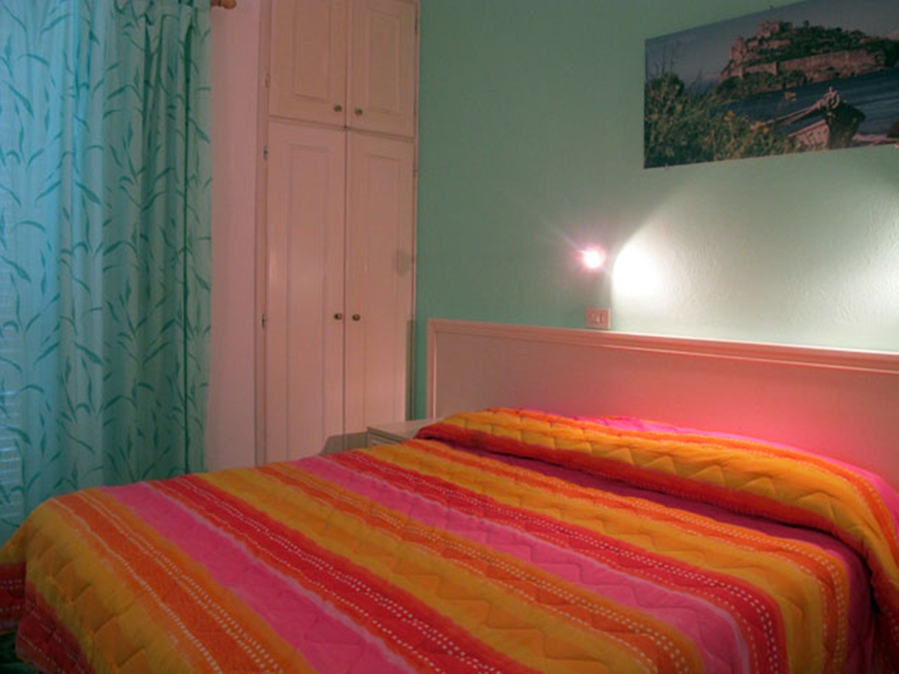 A bedroom with a bed, a wardrobe, and a painting on the wall.