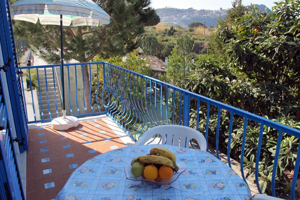 A balcony with a table set for two, a chair, and a fruit bowl.