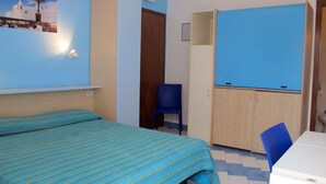 A room with a bed, a blue chair, a wardrobe, and a small table. - Residence Villa Marinù (Forio)