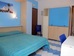 A room with a bed, a blue chair, a wardrobe, and a small table. - Residence Villa Marinù (Forio)