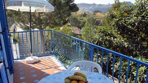 A balcony with a table set for two, a chair, and a fruit bowl. - Residence Villa Marinù (Forio)