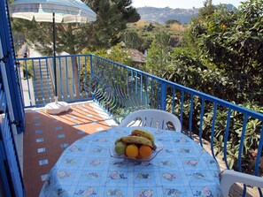A balcony with a table set for two, a chair, and a fruit bowl. - Residence Villa Marinù (Forio)