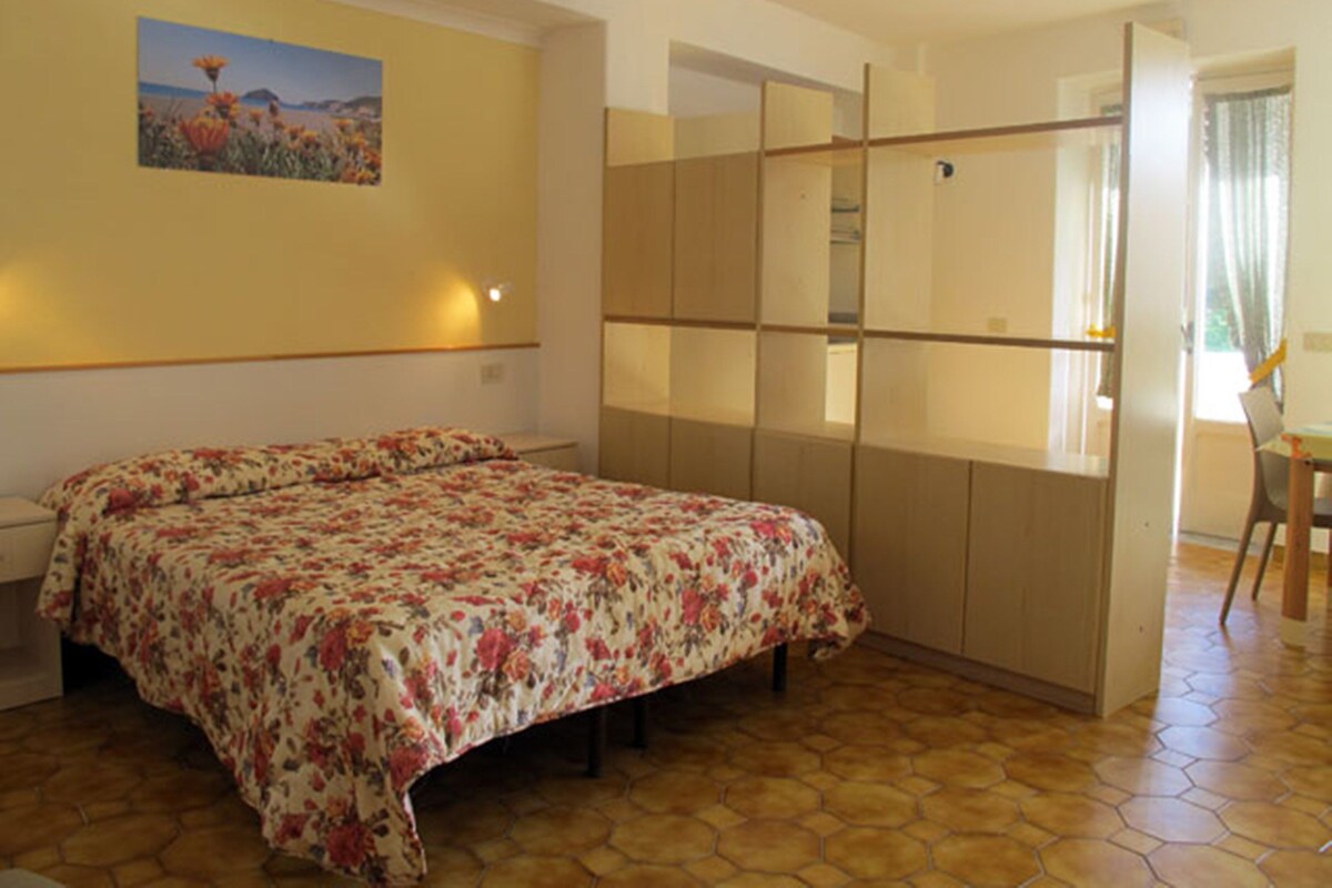 A bedroom with a bed, a nightstand, a desk, and a chair.