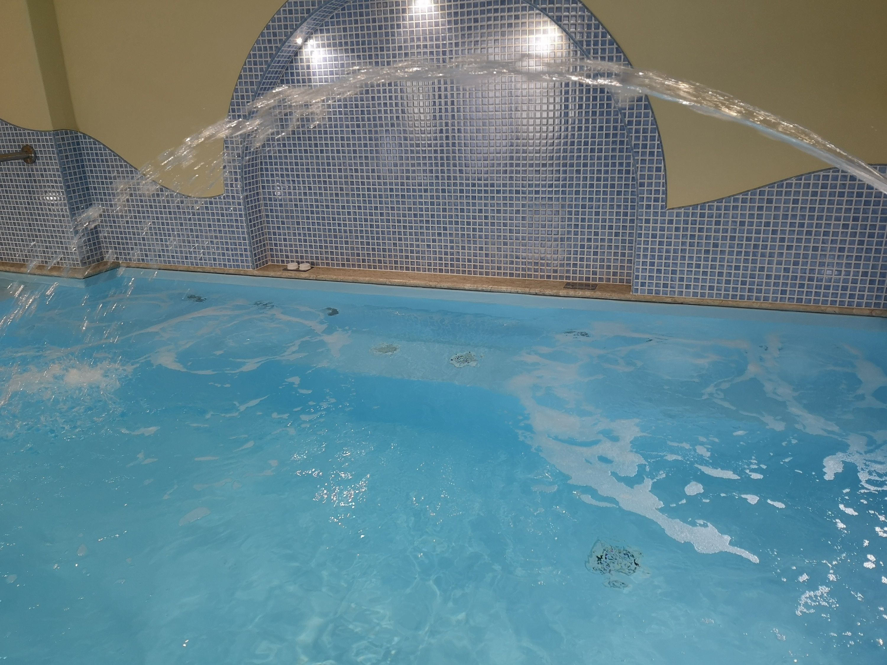 Une piscine à l’eau claire avec un mur carrelé.