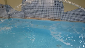 Une piscine à l’eau claire avec un mur carrelé.