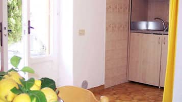 A small kitchen with a sink, a window, and a table with a fruit bowl.