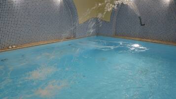 An indoor swimming pool with blue tiled walls and a clear water surface.