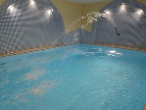 An indoor swimming pool with blue tiled walls and a clear water surface. - Residence Villa Marinù (Forio)