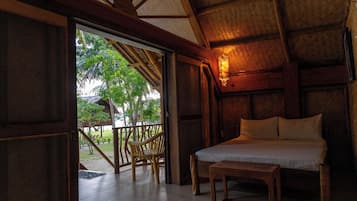 Una stanza con un letto, un tavolo di legno e una sedia. Include un balcone con vista su alberi e un edificio.