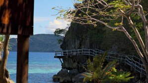 A coastal scene with a wooden structure, a bridge over rocks, and a clear view of the sea. - Sangat Island Dive Resort (Coron)