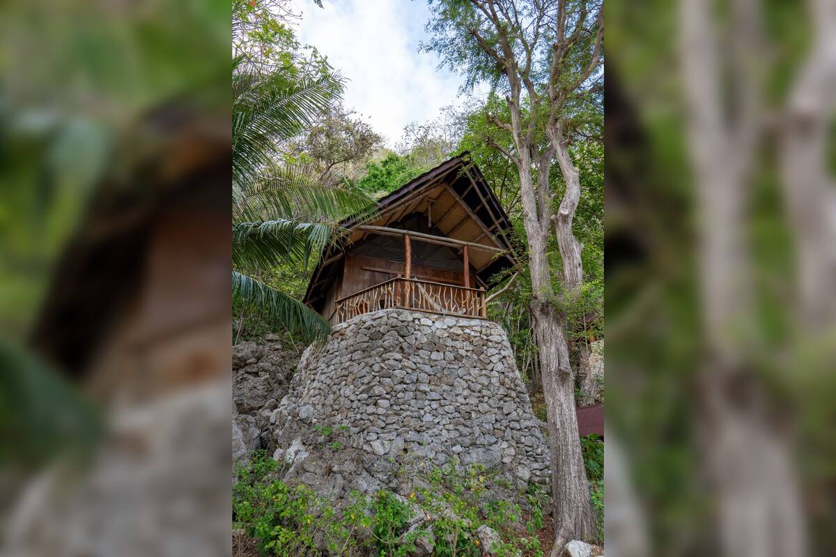 A stone structure with a wooden cabin on top, surrounded by trees.
